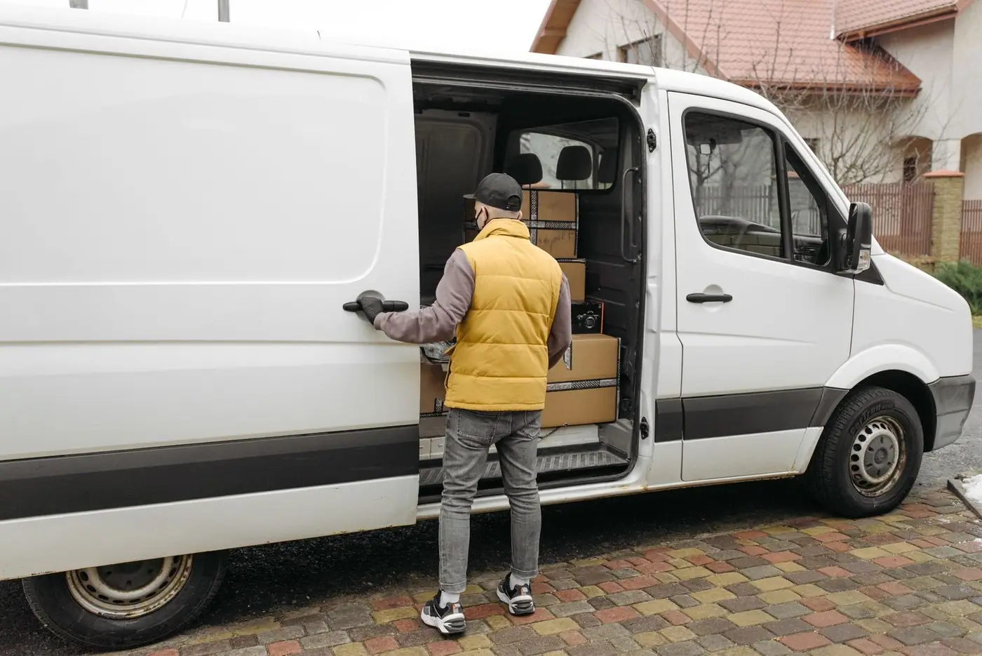 A delivery driver loads packages into a white van on a residential street