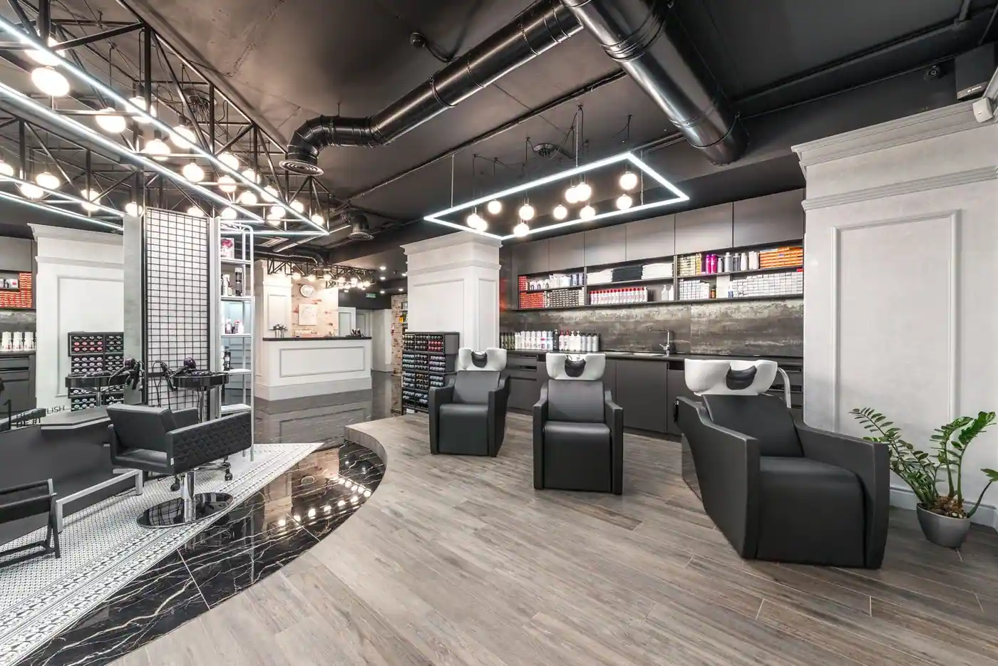 Comfortable backwash chairs with sinks near a potted plant in a bright contemporary beauty salon