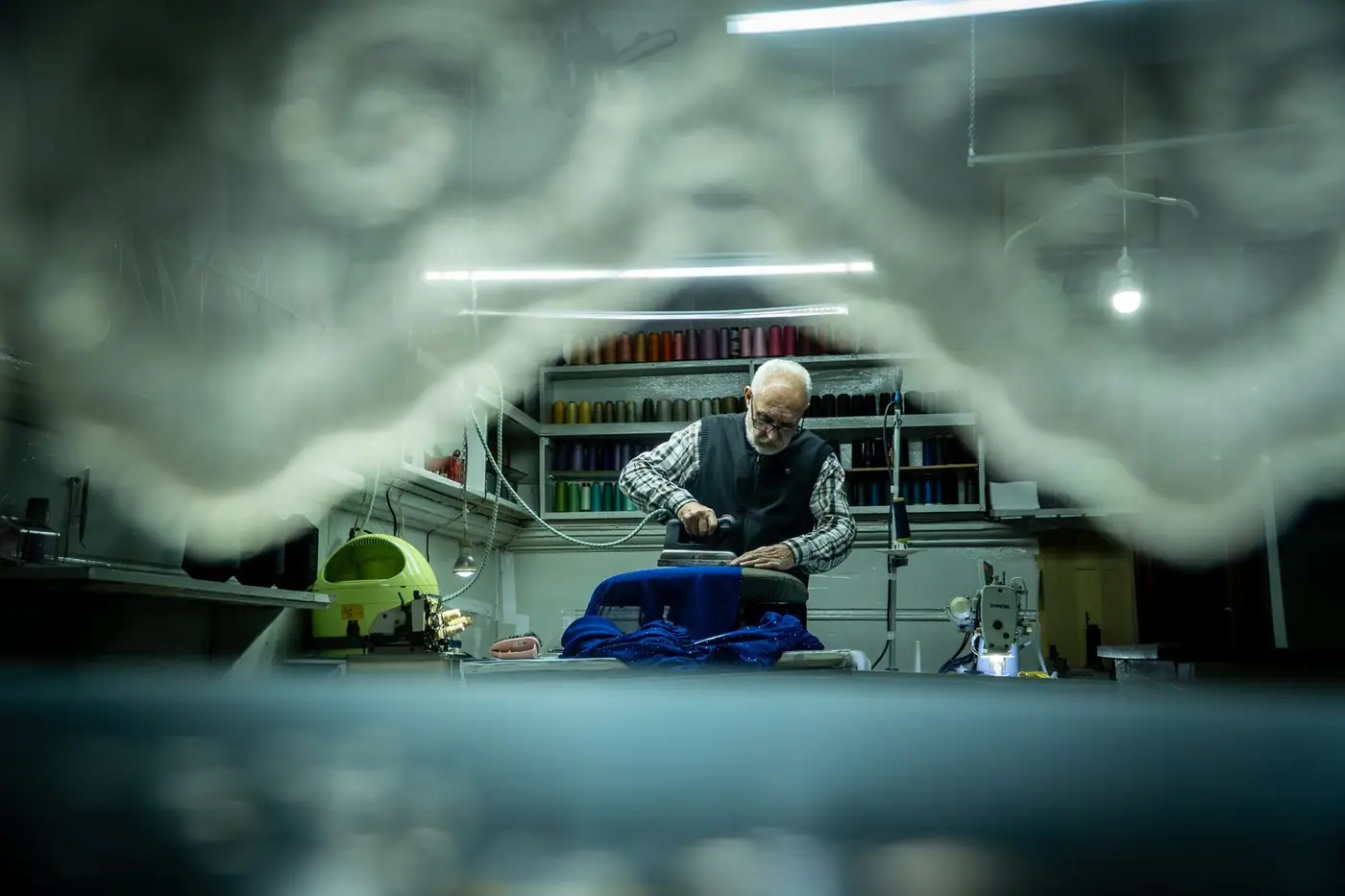 A tailor working carefully on fabric in a workshop