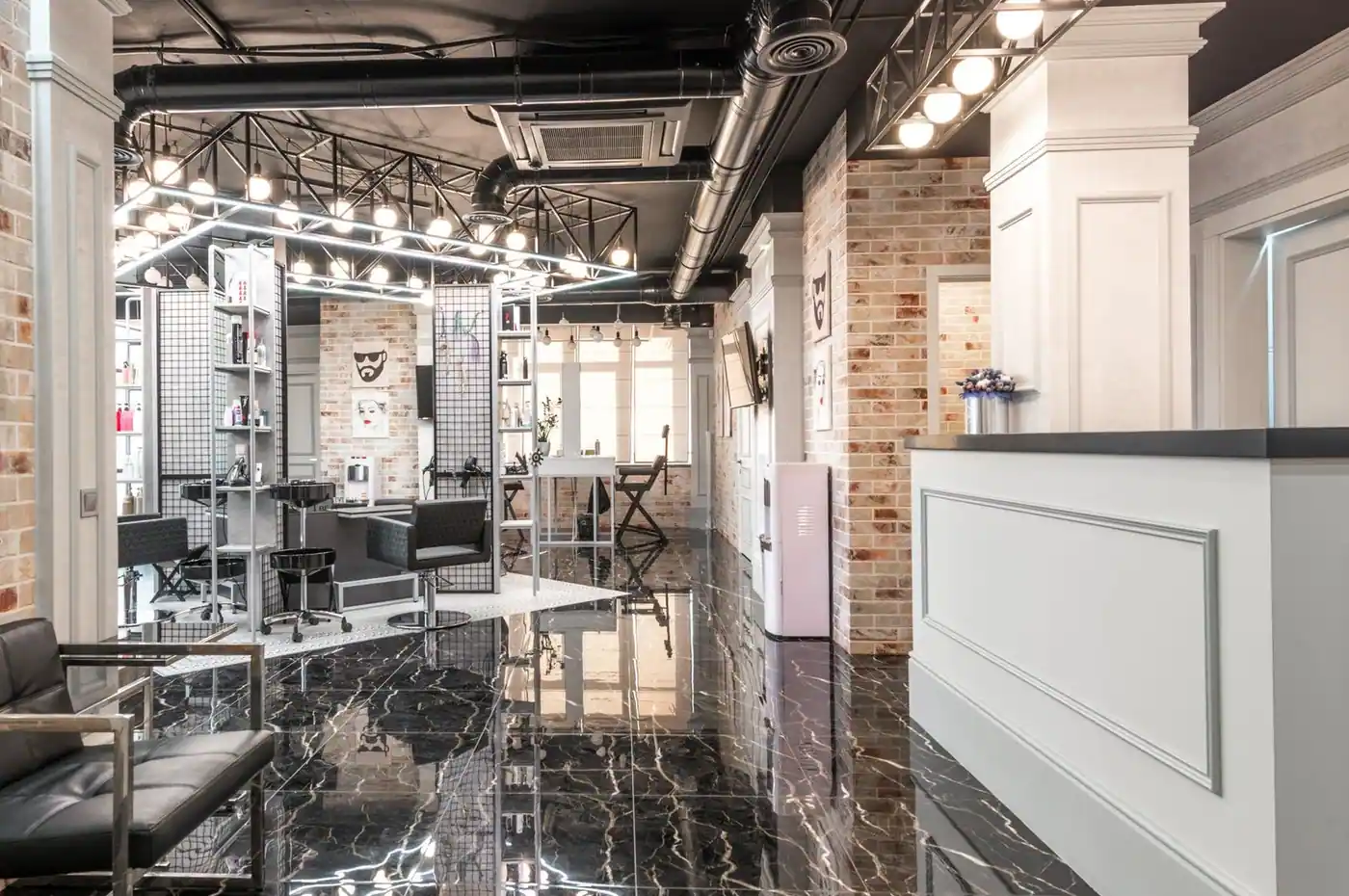 Reception counter placed in spacious stylish beauty salon with black chairs and decorated bricks walls with paintings under bright illuminat