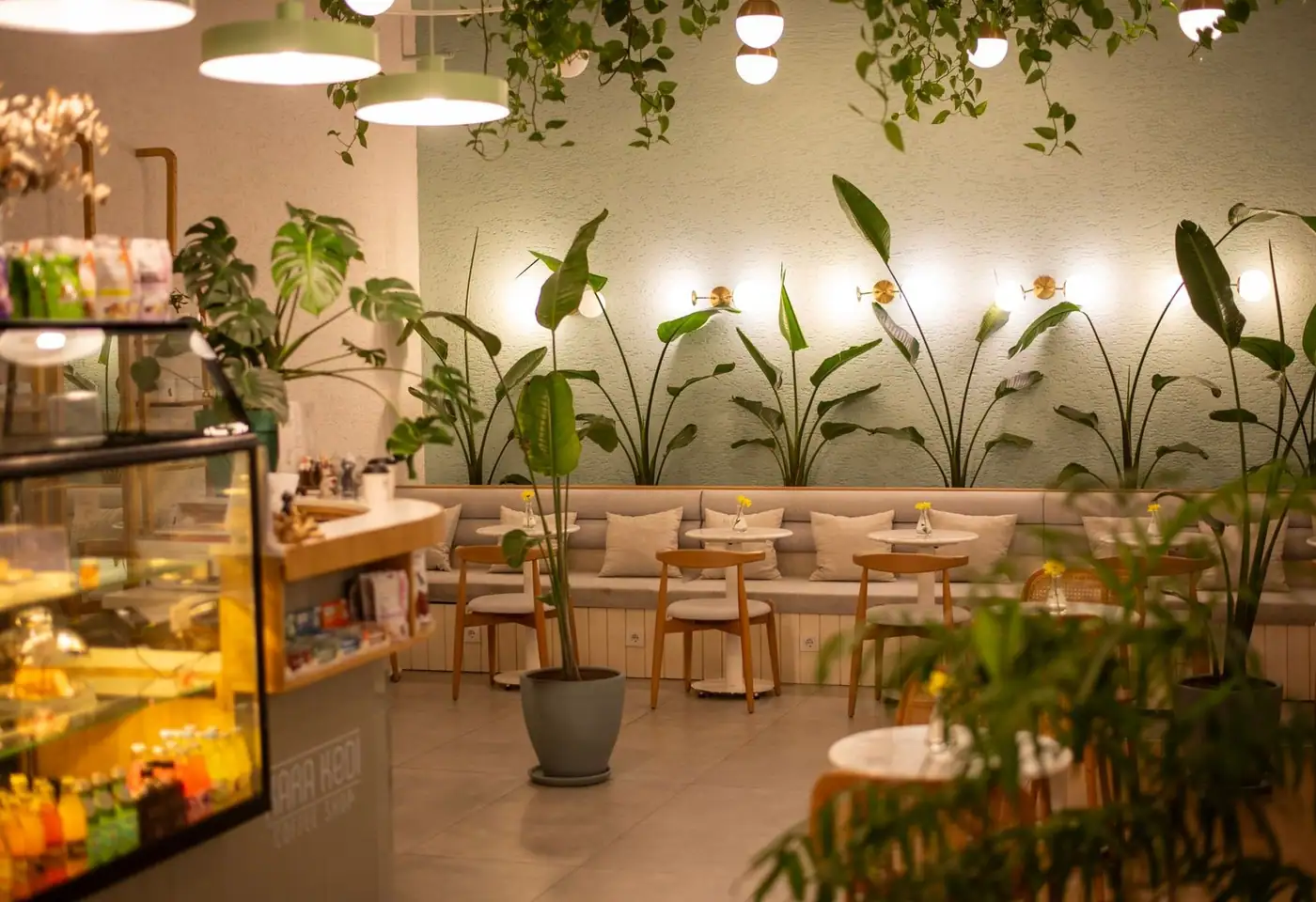 Elegant café interior with plants and warm lighting, creating a cozy ambiance.