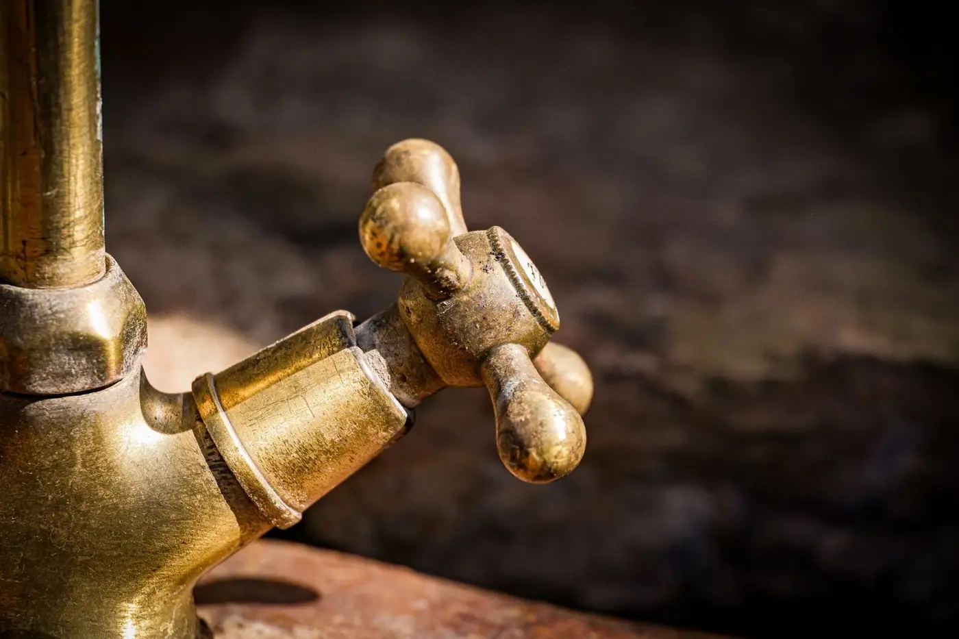 Detailed shot of an old brass faucet handle with rustic texture.