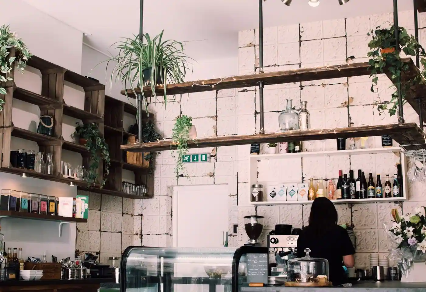 Charming rustic café interior with lush plants and a barista at work, featuring a vintage vibe.