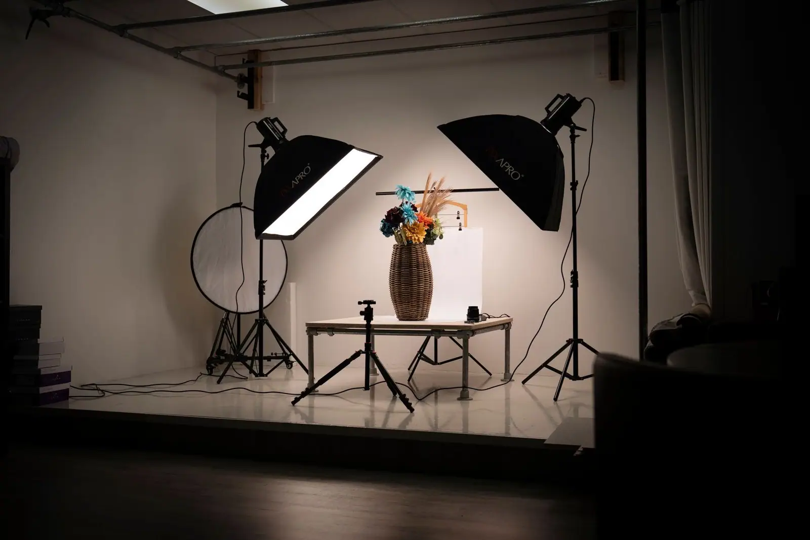 Indoor photography studio setup with lighting equipment and a floral arrangement in a basket