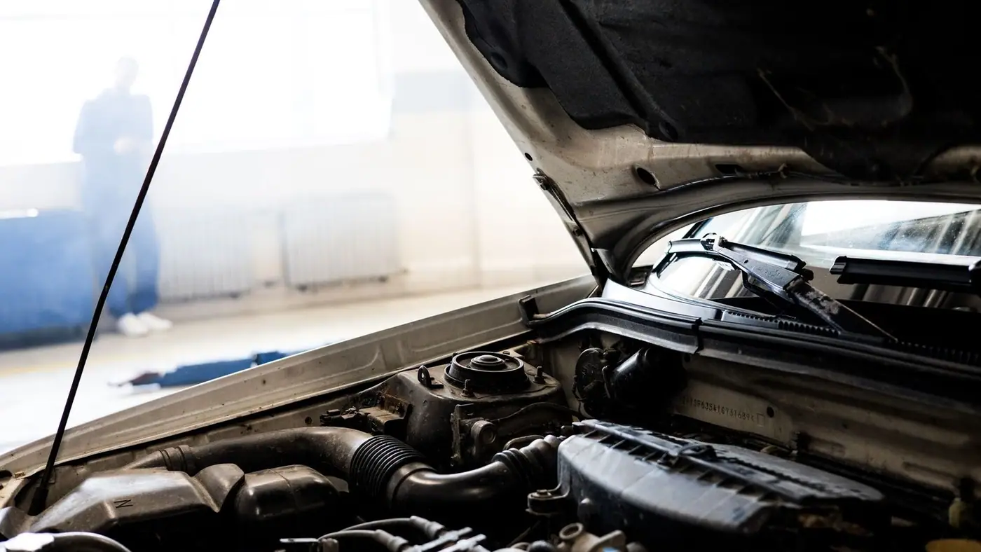 Detailed image of a car engine underneath the open hood in a well-lit indoor garage.