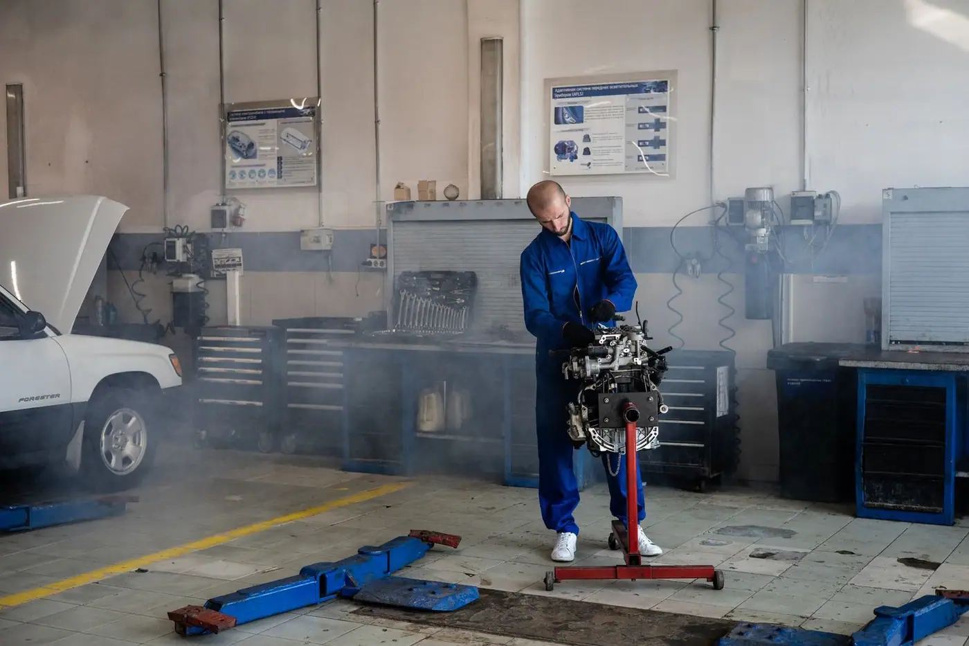 A mechanic repairing a car engine in a busy auto repair shop with tools around.