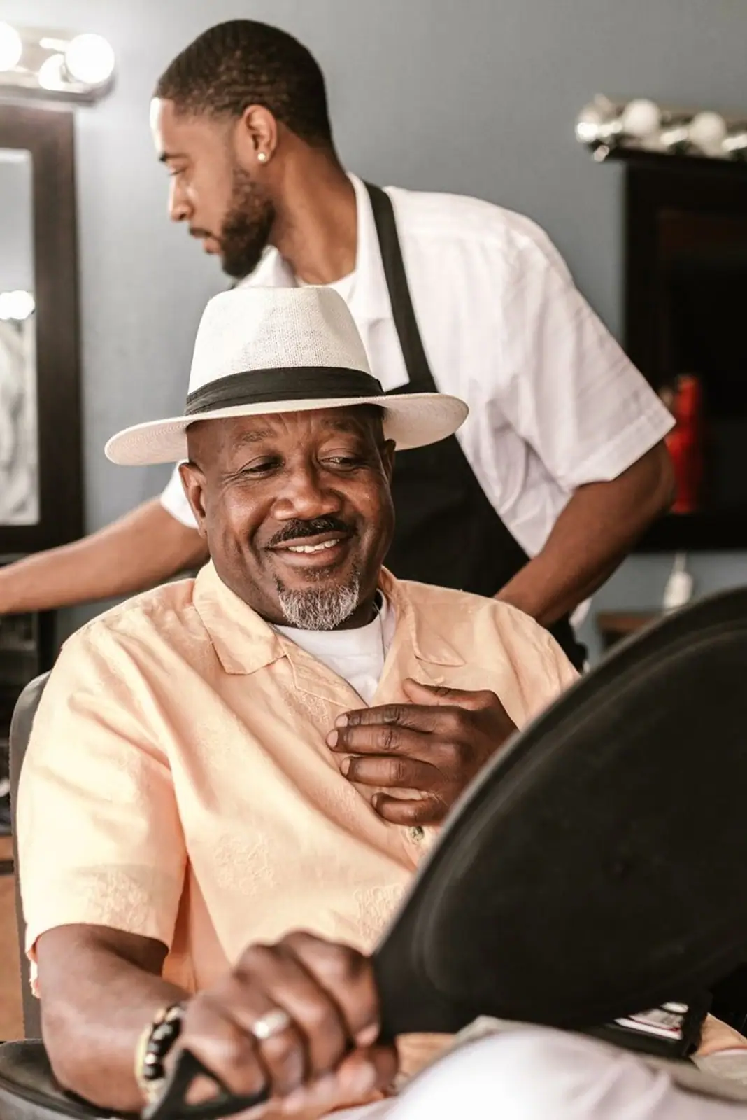 A happy customer enjoys a haircut in a stylish barber shop with a friendly barber.