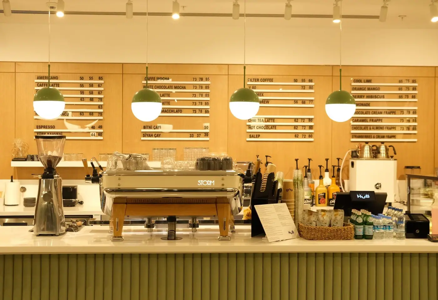 Modern café counter with espresso machine and menu boards under warm lighting.
