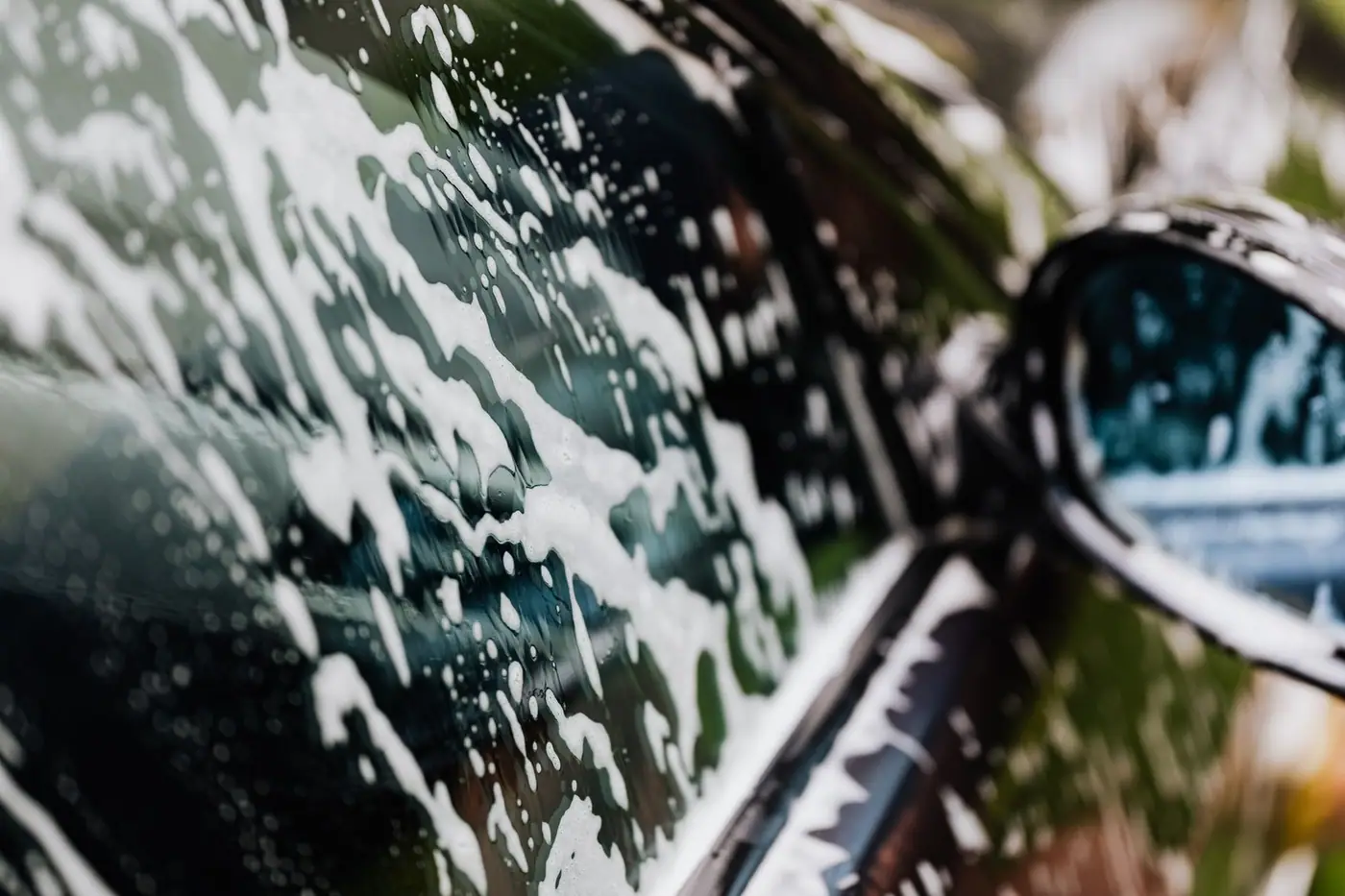 A car covered in soapy foam during a hand wash.