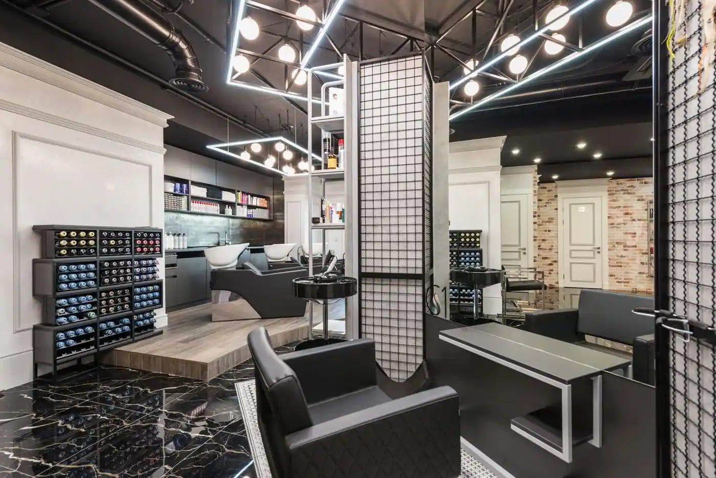 Black leather salon chair in front of a mirror, with backwash chairs and hair products behind