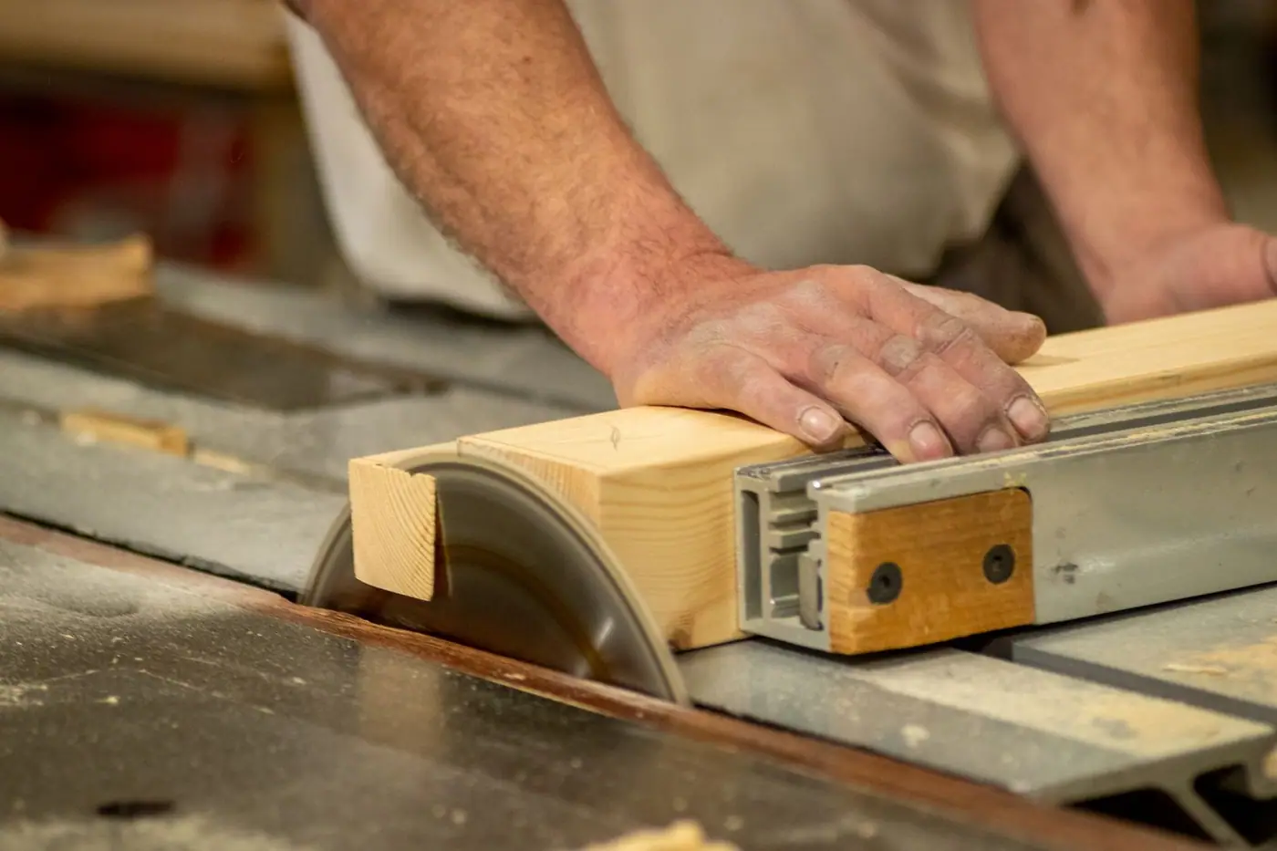 Hands cutting wood on a table saw