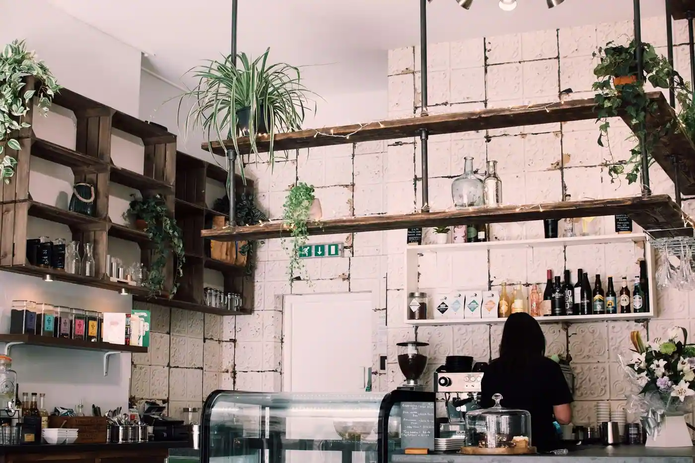 Charming rustic café interior with lush plants and a barista at work