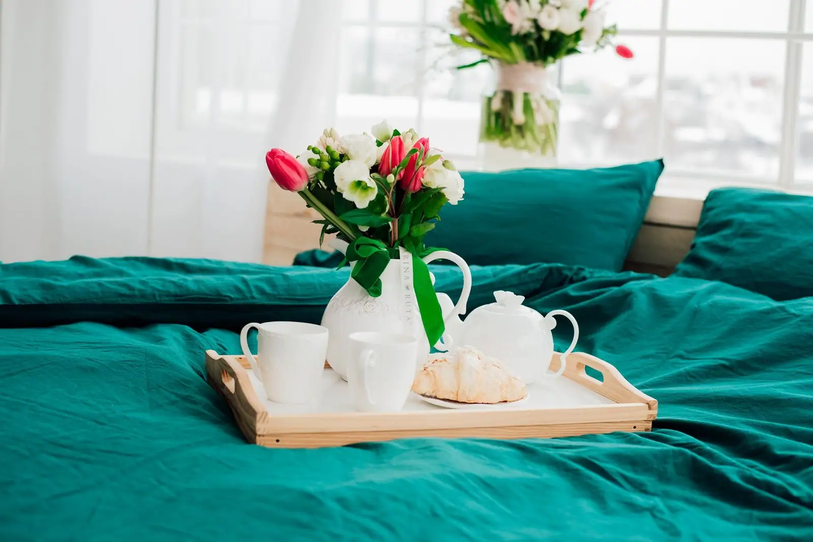 Bright bedroom scene with breakfast tray, flowers, and teal bedding for a peaceful morning vibe.