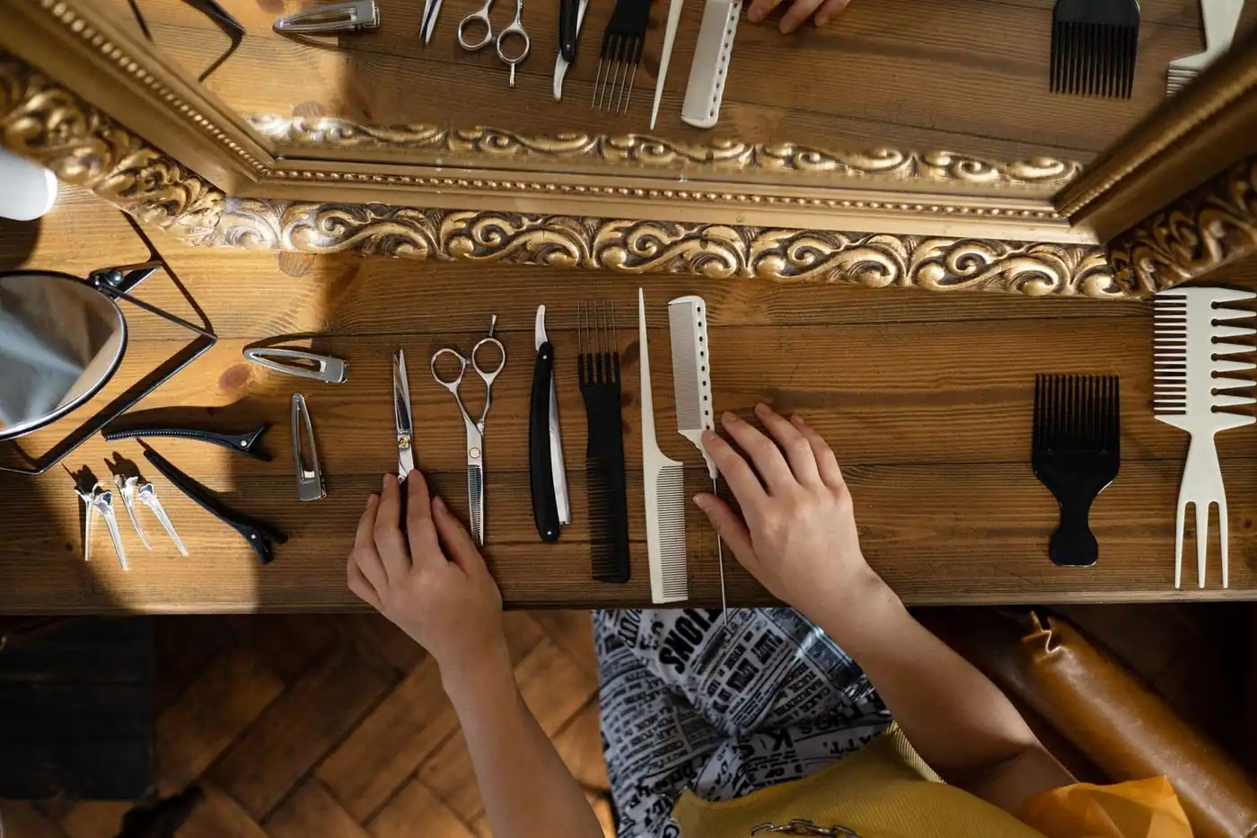 Overhead view of styling tools on a wooden table next to a mirror