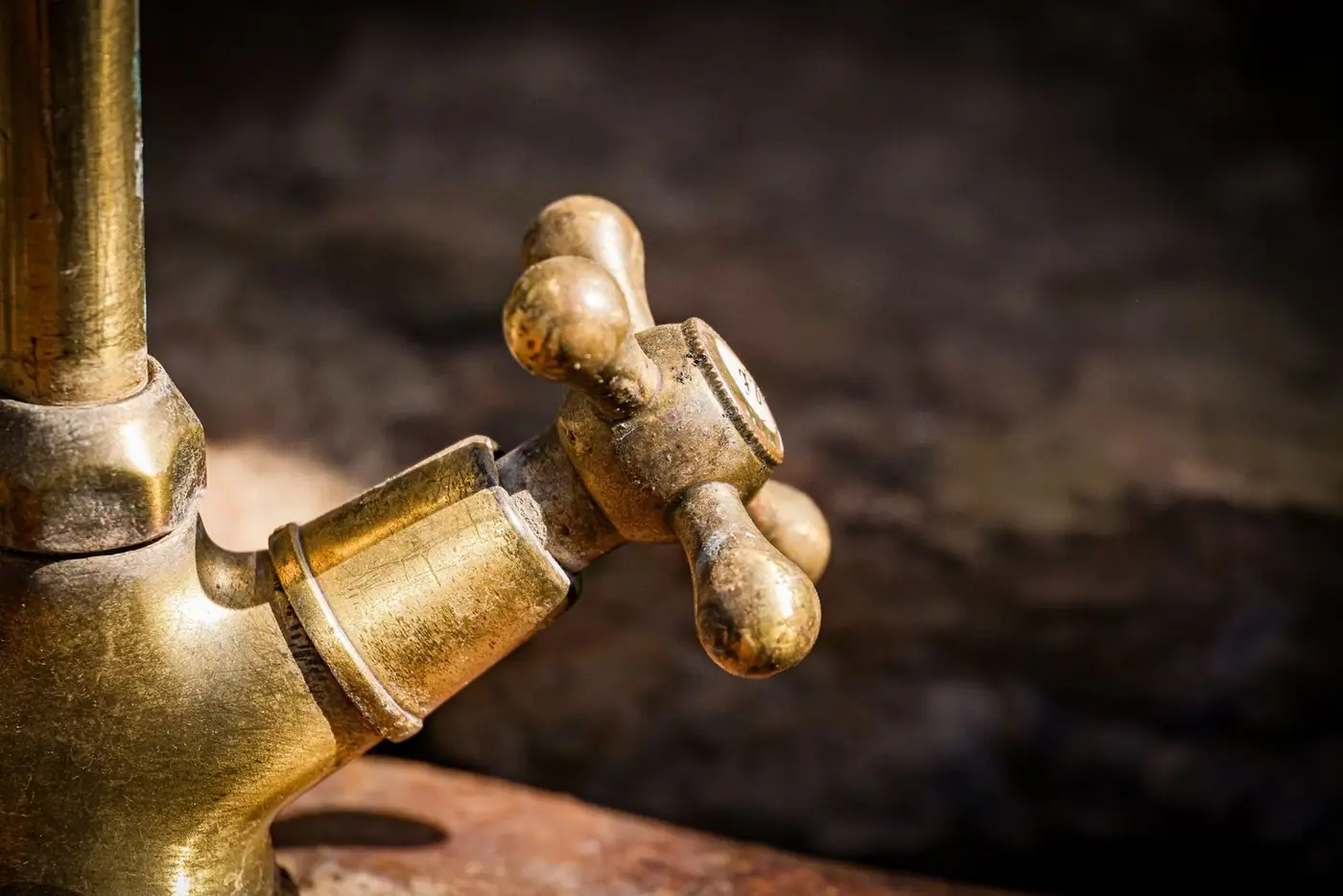 Close-up of an old brass tap handle with a worn, rustic texture