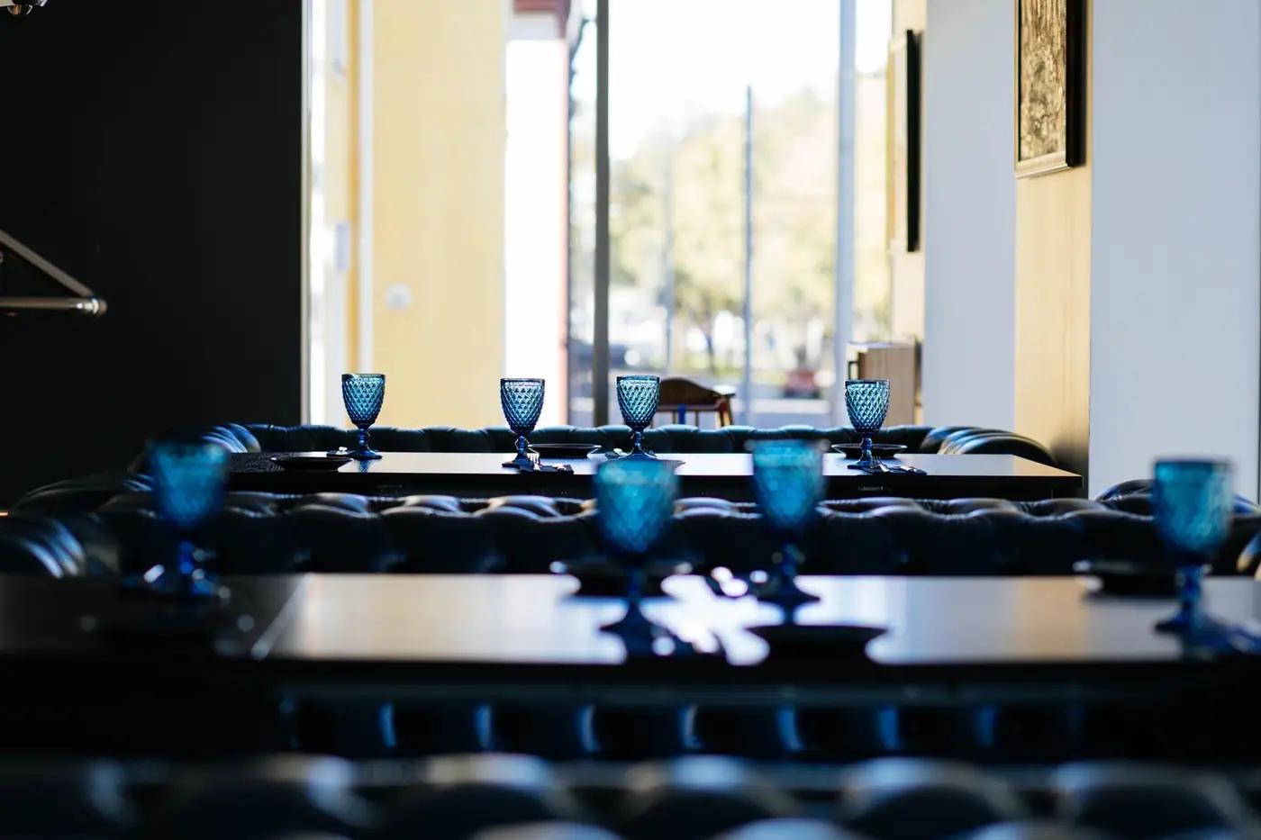 Blue glass goblets set on tables in a chic restaurant interior with modern decor