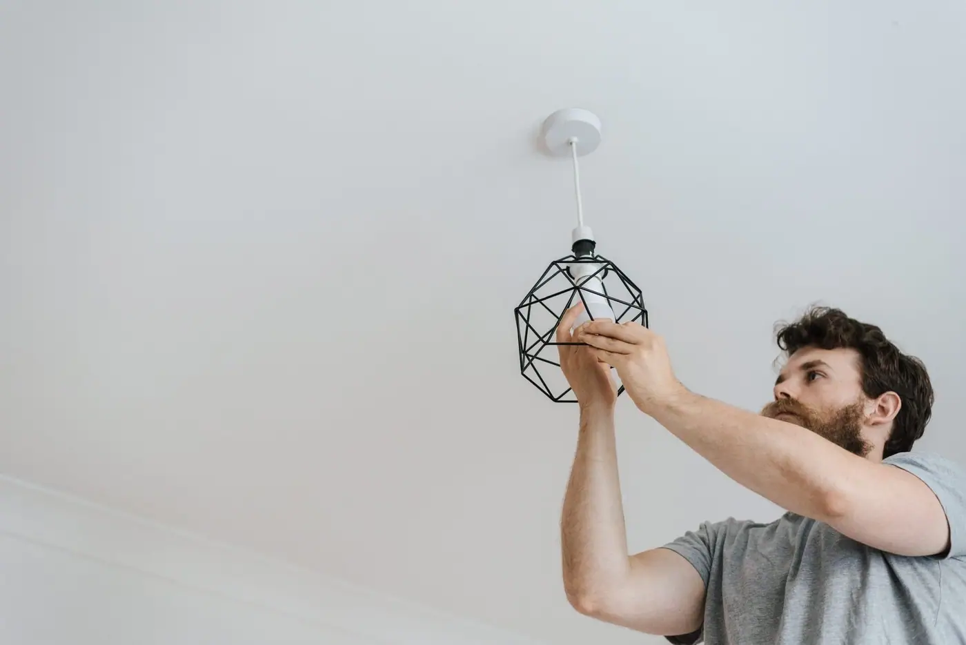 Looking up at someone screwing a light bulb into a new lamp during renovation work