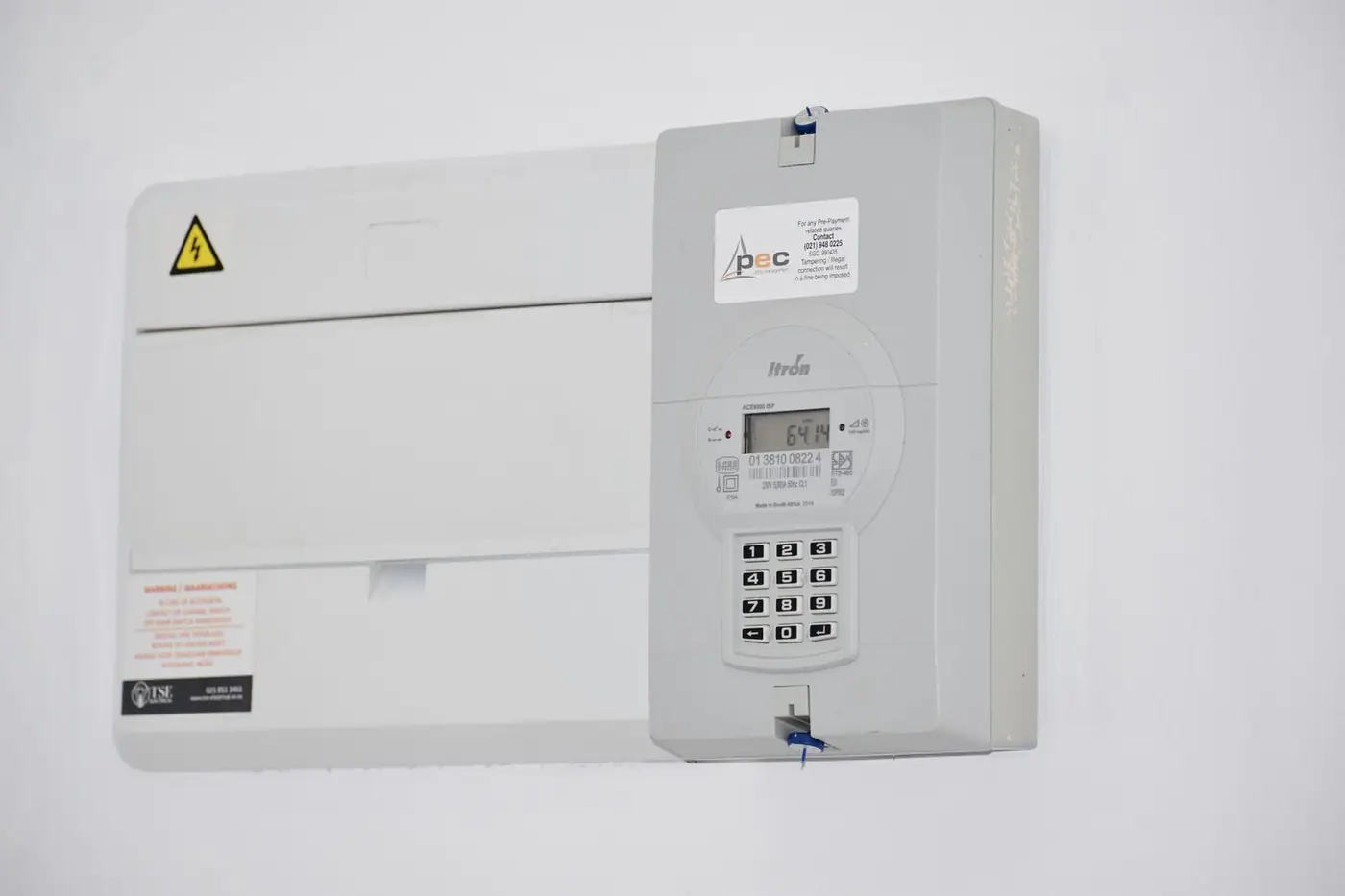 An electrical meter and fuse box mounted on a white wall