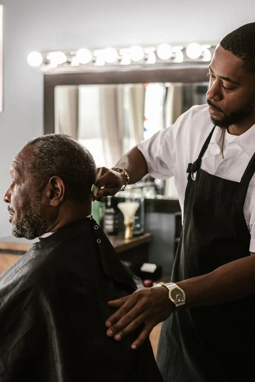A barber meticulously trims a customer's hair in a stylish barbershop setting.