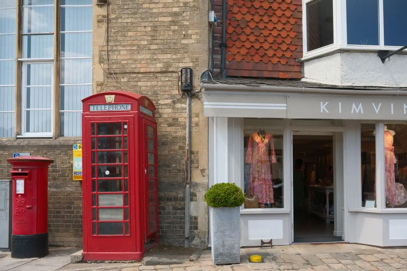 A classic red telephone box and post box outside a boutique